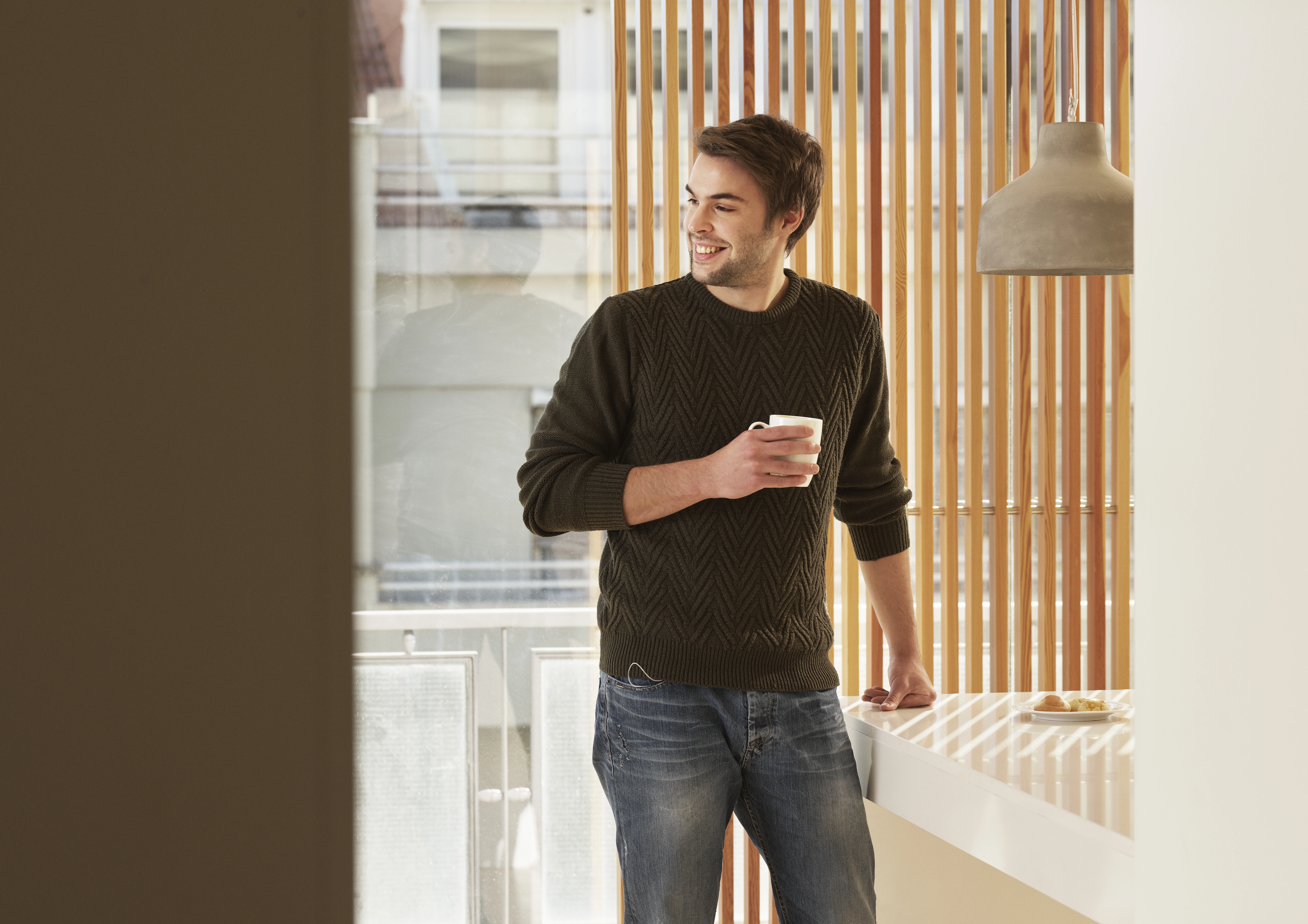 a person standing in front of a window and holding a cup