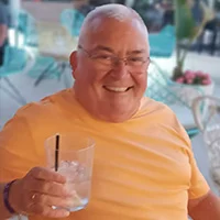 a person smiling and holding a glass