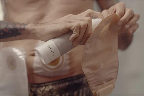 a man applying a spray to an ostomy pouch